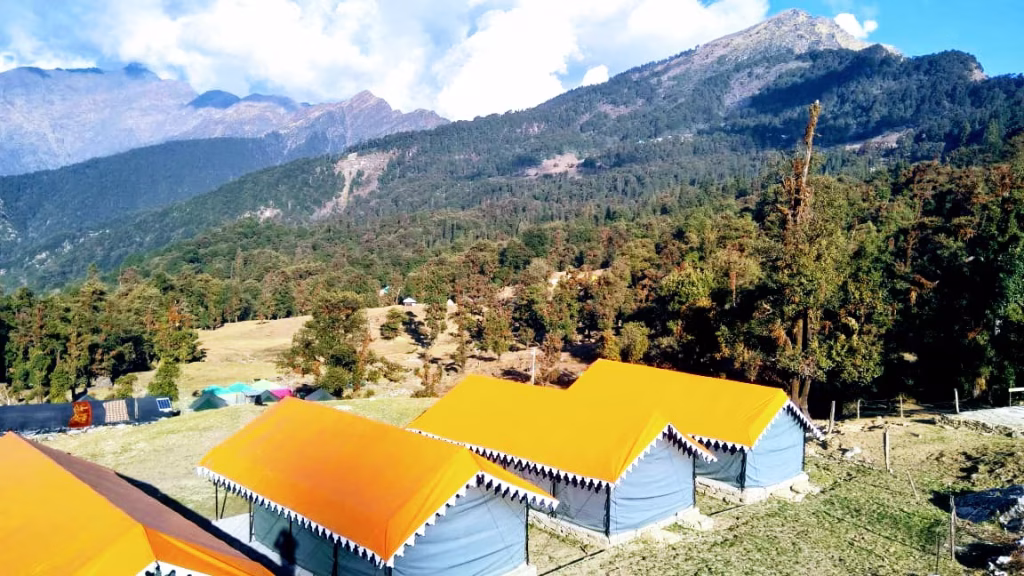 A peaceful campsite with colorful tents set up amidst the lush green meadows of Chopta, Uttarakhand.